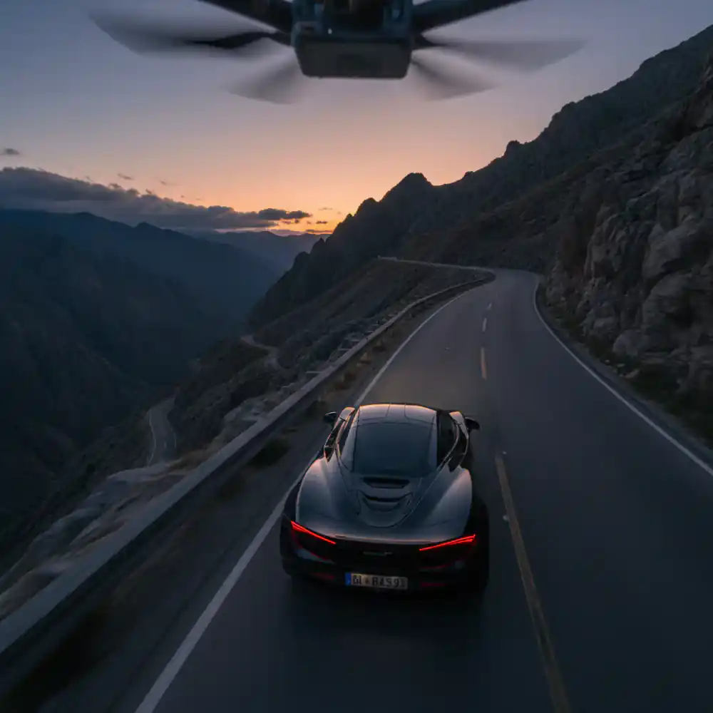 FPV drone following a fast car on a mountain road